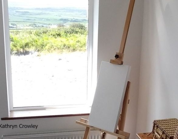 Easel with a canvas on it. There is a view over the valley below through my window. 