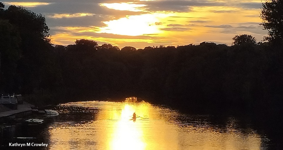 River blackwater at sunset. Two people row in a boat.